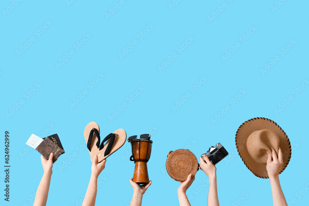 Many hands with beach accessories, passports and djembe on blue background