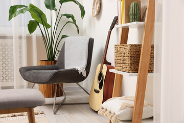 Poster - Spring atmosphere. Wooden shelving unit, acoustic guitar and comfortable chair in stylish room