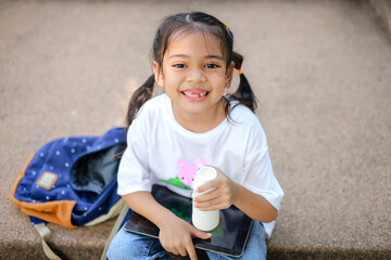 Little kid girl asian holding a bottle of milk in the school. feel happy and enjoy drinking milk before entering the classroom.