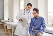 © Studio Romantic - Doctor and patient talking during a medical check up at the hospital. Young woman in a white coat shows good analysis results to a happy young man sitting on the medical couch in the examination room