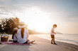 © Garun Studios - Holiday Family on the beach in summer, Travel, vacation and lifestyle concepts. Happy asian family together on the beach in holiday. Parent and baby sitting enjoying the sunset on the beach.