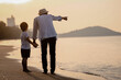 © Garun Studios - Holiday Family on the beach in summer, Travel, vacation and lifestyle concepts. Happy family holidays. Joyful father, baby son walk with fun along edge of sunset sea surf on and beach.