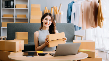 Startup small business SME, Entrepreneur owner woman using smartphone or tablet taking receive and checking online purchase shopping order to preparing pack product box. .