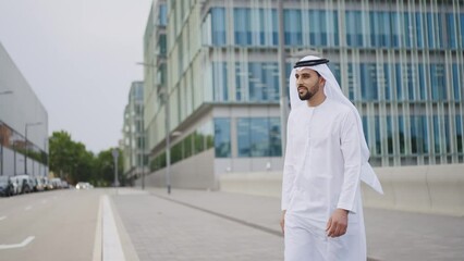 Wall Mural - Handsome businessman with the traditional emirates white outfit working outdoor in Dubai city. Concept about middle eastern cultures and business