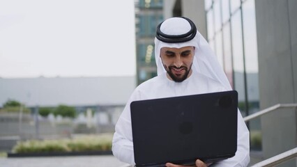 Wall Mural - Handsome businessman with the traditional emirates white outfit working outdoor in Dubai city. Concept about middle eastern cultures and business