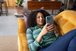 © ReeldealHD images - Young adult woman using smartphone lying on sofa