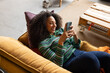 © ReeldealHD images - Young adult woman posting on social media lying on sofa