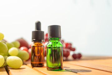 two bottles of essential oils. natural cosmetics for skin care. A bottle and fresh peaches and grapes on a wooden table. Taking care of health and beauty.