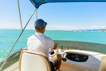 Bach View Of Middle-aged Man Driving Luxury Motor Yacht. Captain At The Helm Of Motor Boat.