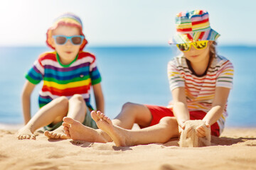 Wall Mural - Boy and girl sitting on the sand near the sea.