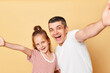 © sementsova321 - Excited amazed laughing family father and daughter wearing casual t-shirts standing isolated over beige background screaming with happiness making selfietogether