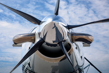 Detail Of The Spinner, Blades, Exhaust And Intake Of A Turboprop Aircraft. Chrome Nose Cone And Propeller In The Front With A Blue Skies And High Cirrus Clouds In The Background.