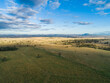 © Austockphoto - Aerial view of flat Aussie farm paddock with sunlight on grass and hills in distance