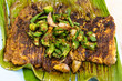 Close-up overhead view of grilled stingray fish with spices topped with okra vegetable on banana leaf popular food in Malaysia