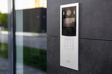 Entrance Doorbell In A Multi-apartment Building, With A Video Surveillance Camera, On A Dark Wall.