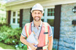Man with a white hard hat holding a clipboard, inspect house