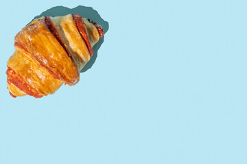 Wall Mural - Sweet croissant on blue background with copy space.