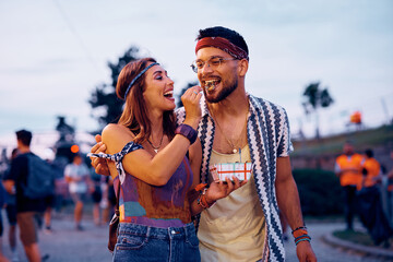 Wall Mural - Happy couple eats mini donuts at open air music festival.