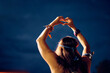 Rear view of woman making heart shape with hands while attending summer music festival.