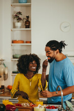 A Happy African American Couple Is Cooking And Trying Out Food At Home.