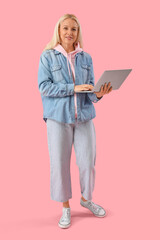 Canvas Print - Mature female programmer working with laptop on pink background