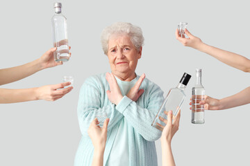 Poster - Senior woman rejecting vodka on light background