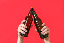 Male Hands With Bottles Of Cold Beer Clinking On Red Background
