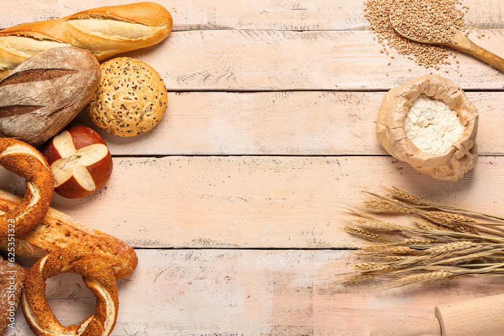 Composition with different types of bread, wheat ears and flour on white wooden table