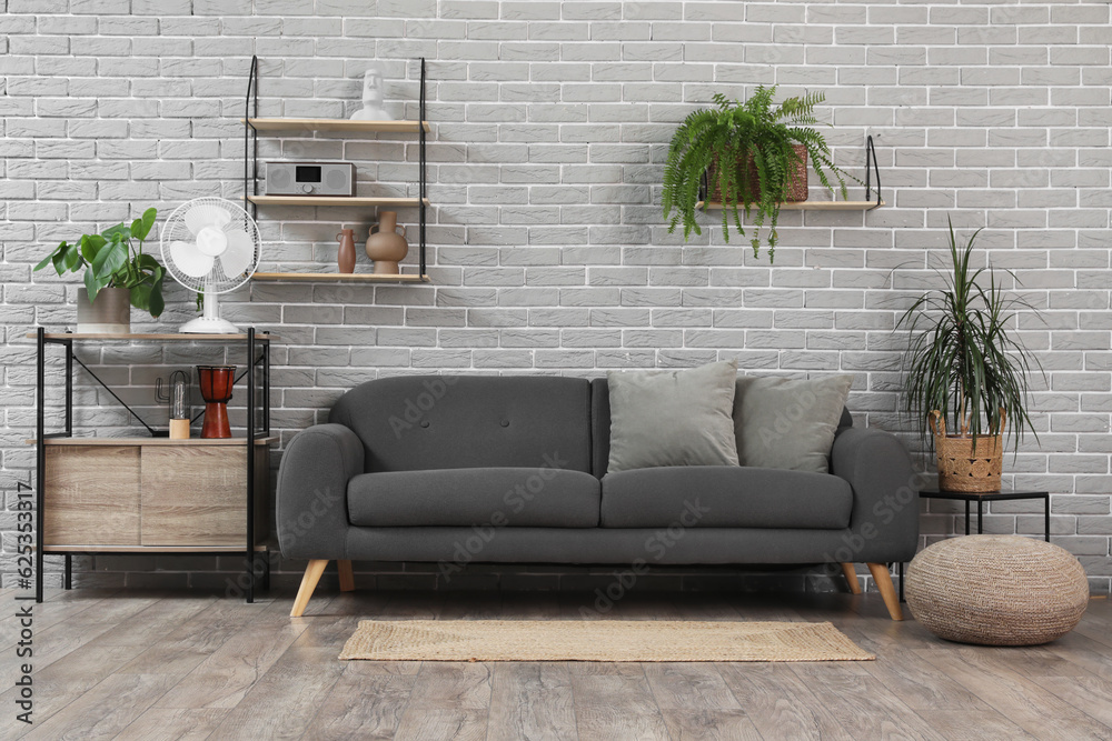Interior of modern living room with sofa and electric fan on shelf