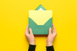 Female hands with envelope and blank card on yellow background, closeup