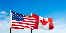 USA And Canada Flags Against Blue Sky Background