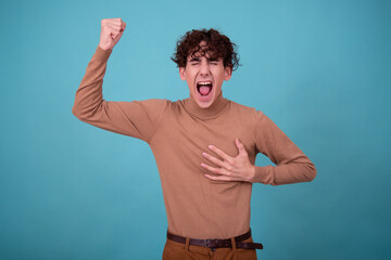 Wall Mural - Emotional guy is surprised, happy and sad posing in the studio on a blue background.