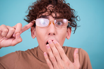 Wall Mural - Emotional guy is surprised, happy and sad posing in the studio on a blue background.