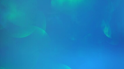 Wall Mural - Green Bokeh Movement On Blue Background. Abstract Christmas bokeh background. Shiny defocused blurry circles slow motion. Magic artistic shiny light leaks.