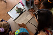 High angle view of diverse teacher and students studying online over laptop in school classroom