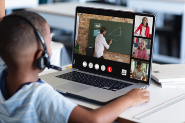 Poster - African american boy in headphones listening to teacher teaching over video call on laptop