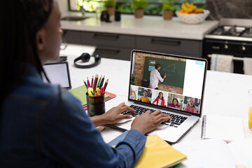 Canvas Print - African american teenage boy looking at laptop screen with students and teacher during video call