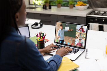 Poster - African american teenage boy looking at laptop screen with teacher and students during video call
