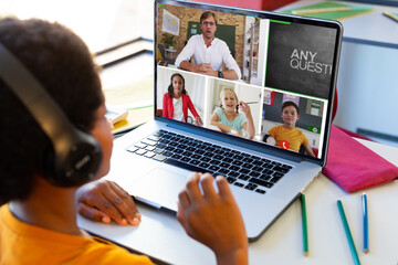 Poster - Biracial boy wearing headphones and listening to online class over laptop at home