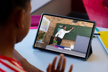 Poster - African american boy looking at male teacher teaching online over digital tablet at home