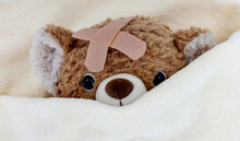 Sick Teddy Bear Toy With Patch In On Head Lying In Bed