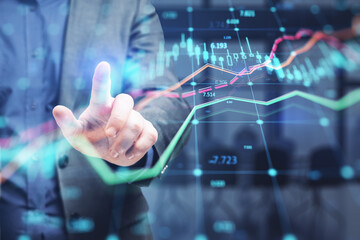 Wall Mural - Close up of businessman hand pointing at glowing forex index chart with grid on blurry office interior background. Market, finance and online trading concept. Double exposure.