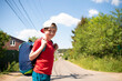 © Ruslan Russland - a boy with a big sports bag came for summer holidays in the village, countryside. portrait of a happy child on the road, village street in summer