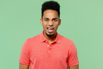 Wall Mural - Young dissatisfied displeased disappointed sad man of African American ethnicity wears pink t-shirt looking camera isolated on plain pastel light green background studio portrait. Lifestyle concept.