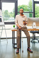 Wall Mural - inclusion, myasthenia gravis syndrome, bold african american man standing with walking cane and coffee to go, computer monitor, dark skinned office worker in smart casual attire