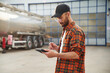 © standret - Holding tablet. Young truck driver in casual clothes