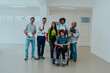 © Minet - A group of students with a professor and a colleague who is in a wheelchair are standing together in the corridor of a modern university