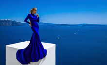 Elegant Woman In Blue Long Sequin Dress Is Posing Outdoor In Luxury Resort In Santorini. Female Model In Amazing Long Dress. Vogue. Couture.