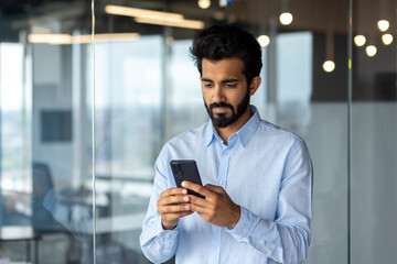 indian young businessman sitting in an office center and using the phone
