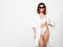 Portrait Of Young Beautiful Sexy Woman In White Robe. Smiling Carefree Model Wearing Pure Underwear. Hot Brunette  Posing Near Wall In Studio Interior. Perfect Body. Slim And Fit. In Sunglasses